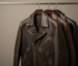 Black and brown custom leather jackets hanging on a rail in a studio